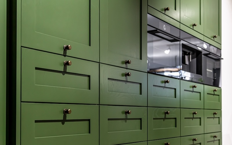 Large green kitchen cabinet with many handles, close-up.